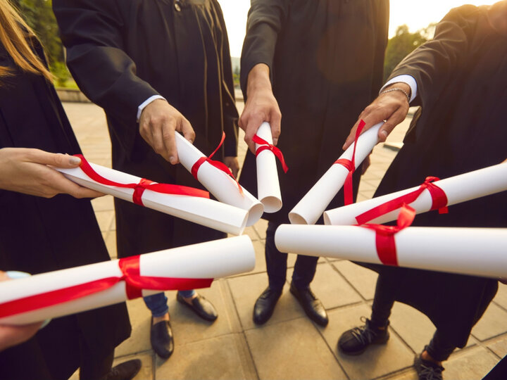 People holding diplomas in a circle.